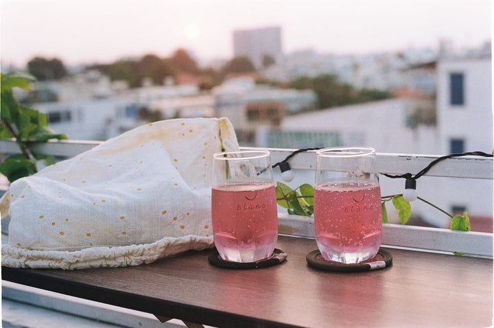 Two pink sparkling spritz cocktails on a rooftop table at sunset