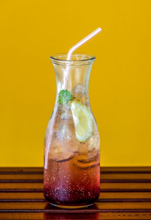 Clear glass pitcher filled with colorful cocktail drinks for a summer BBQ