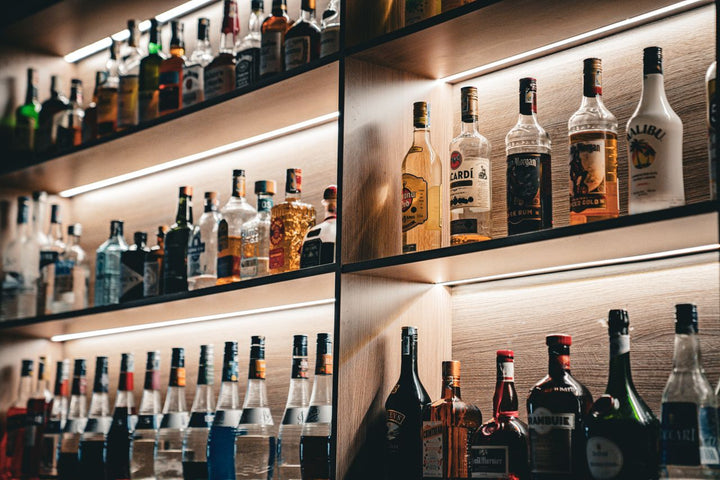 Illuminated bar shelves displaying rows of liqueur and spirit bottles