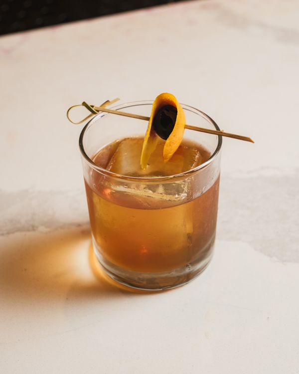 Classic Old Fashioned cocktail with orange peel garnish on marble surface