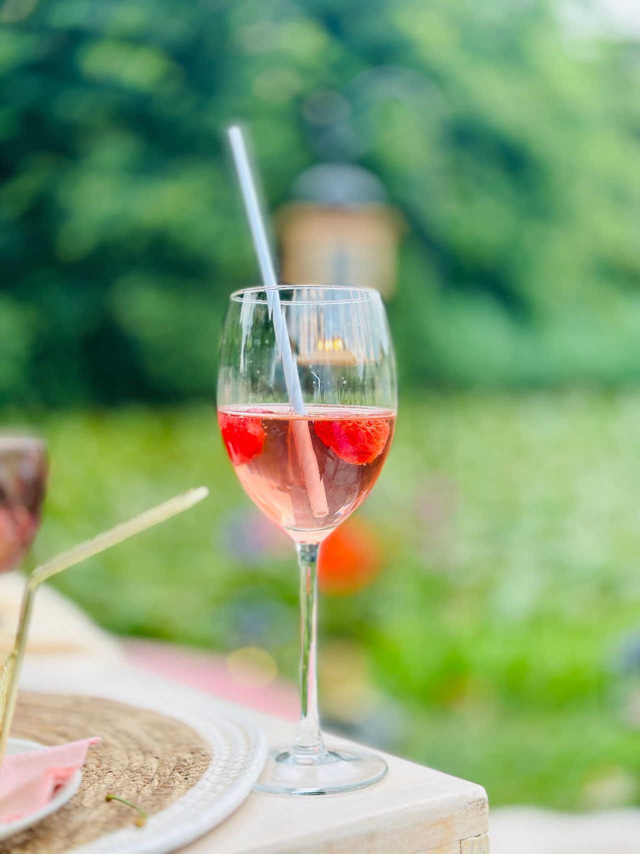 Pink rosé wine in glass with strawberries outdoors in garden