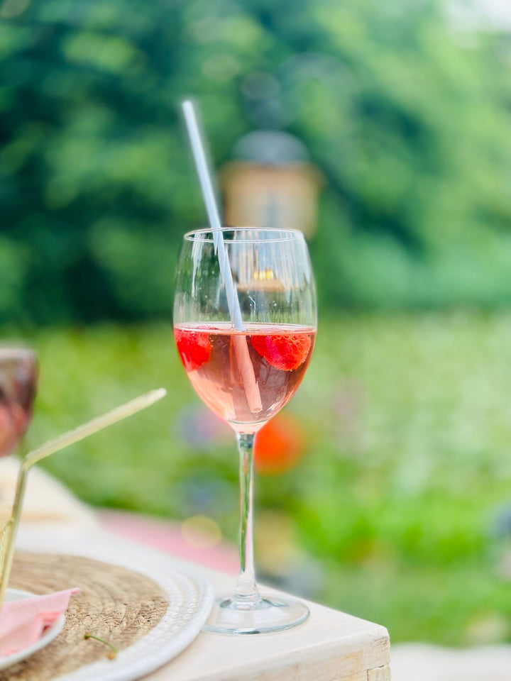 Pink rosé wine in glass with strawberries outdoors in garden