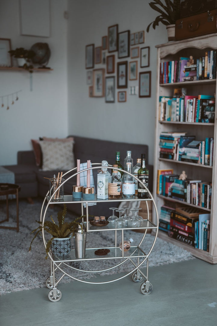 Stylish home bar cart with bottles in a cozy living room interior