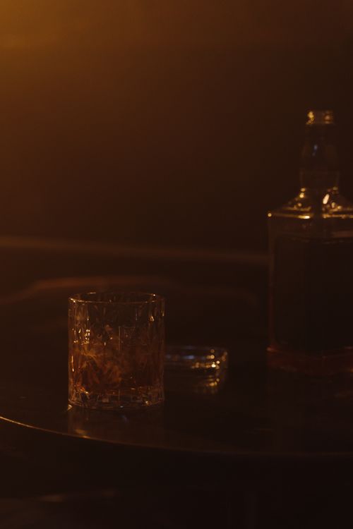 Glass and bottle of whiskey on a wooden table for a Bills game tailgate