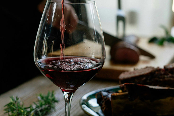 Two glasses of red wine being toasted