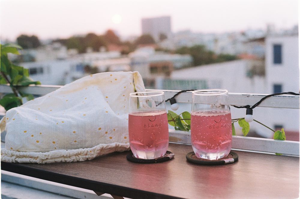 Two pink sparkling spritz cocktails on a rooftop table at sunset